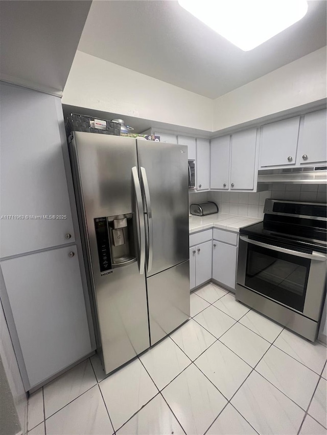 kitchen with light tile patterned flooring, appliances with stainless steel finishes, and backsplash