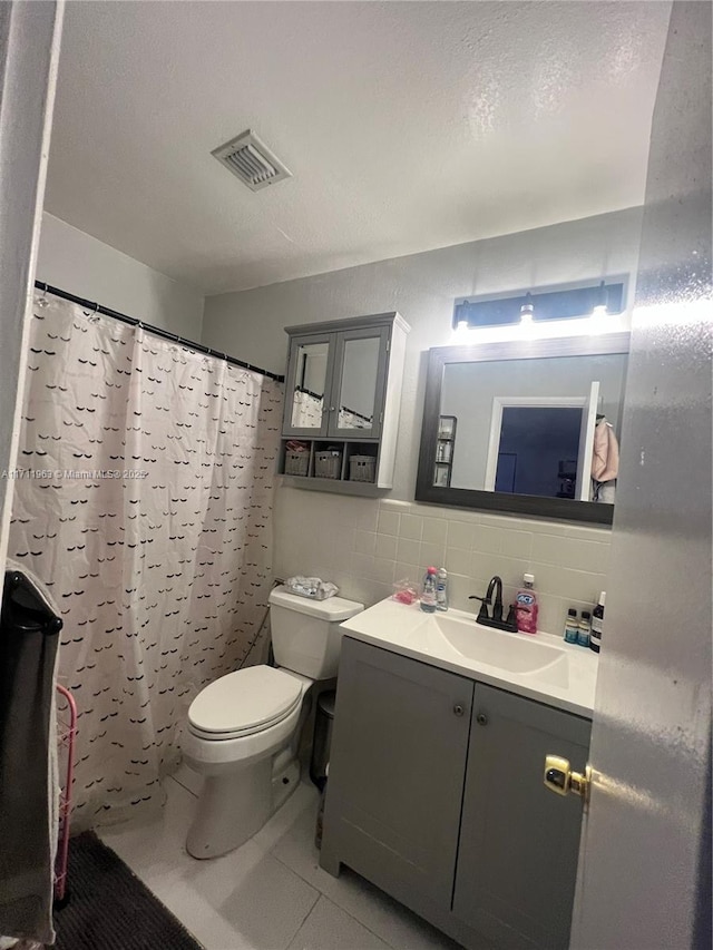 bathroom with toilet, tile walls, vanity, curtained shower, and tile patterned flooring