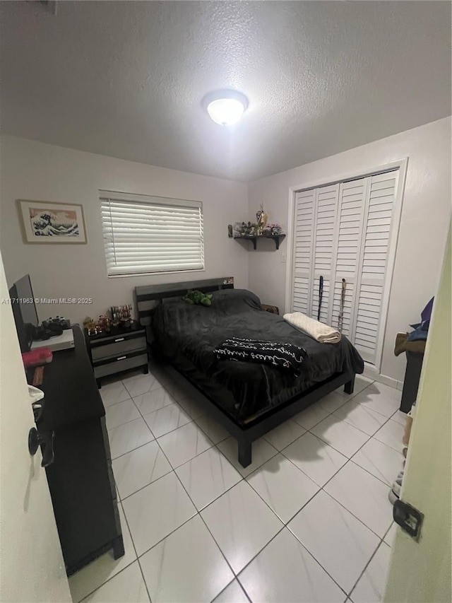 bedroom with light tile patterned floors, a textured ceiling, and a closet