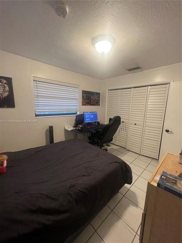 bedroom with light tile patterned floors, a textured ceiling, and a closet