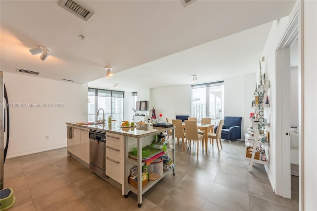 kitchen featuring stainless steel dishwasher, sink, a kitchen island with sink, and a wealth of natural light