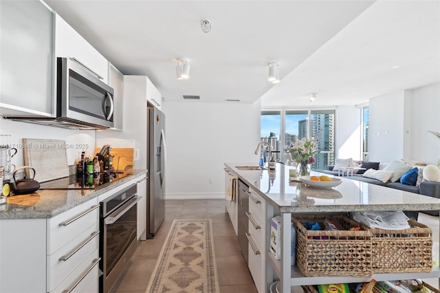 kitchen with stainless steel appliances, visible vents, a kitchen island with sink, a sink, and white cabinetry