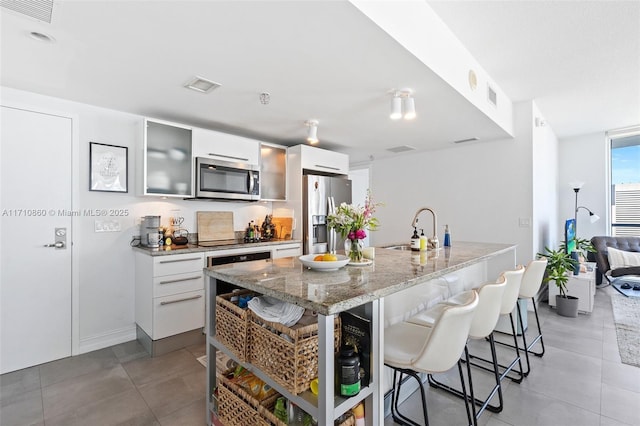 kitchen featuring stainless steel appliances, modern cabinets, a sink, and a kitchen bar