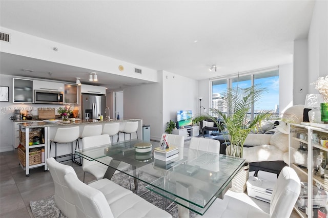 dining area featuring a wall of windows, visible vents, and baseboards