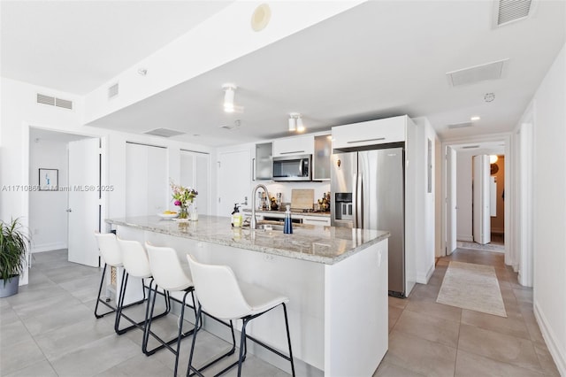 kitchen featuring stainless steel appliances, visible vents, a sink, and a breakfast bar area