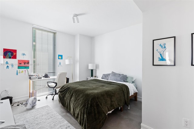 bedroom with finished concrete floors and baseboards