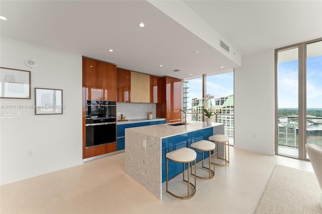 kitchen featuring modern cabinets, expansive windows, tasteful backsplash, visible vents, and a breakfast bar