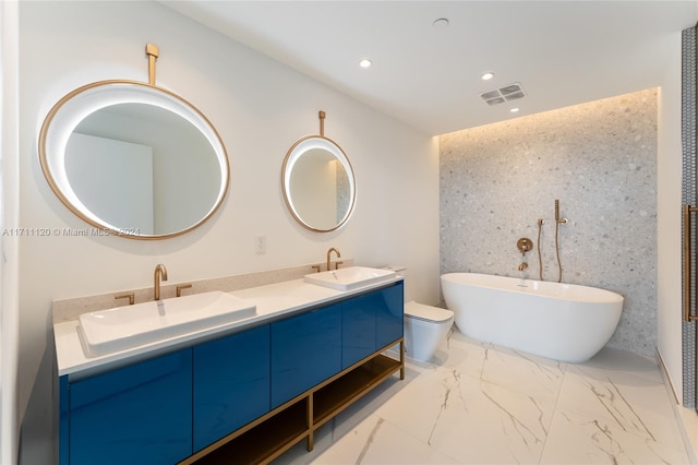 bathroom with vanity, a tub to relax in, and toilet