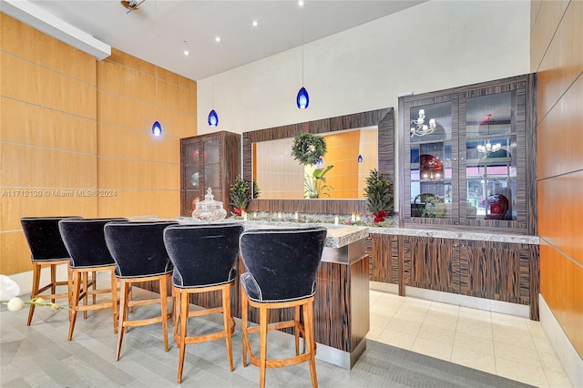 interior space featuring a high ceiling, light tile patterned floors, pendant lighting, and a kitchen breakfast bar