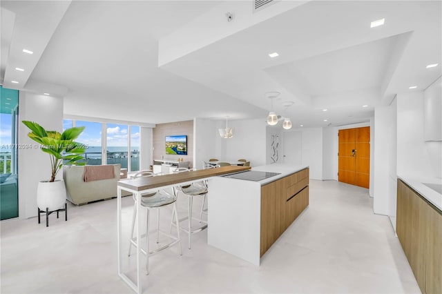 kitchen featuring a spacious island, a wall of windows, decorative light fixtures, and a breakfast bar