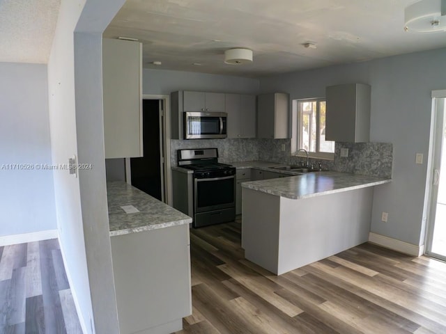 kitchen featuring dark hardwood / wood-style floors, sink, kitchen peninsula, and stainless steel appliances