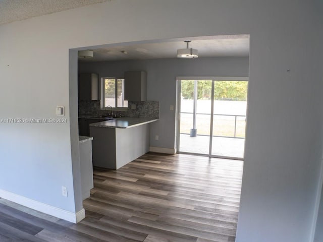 kitchen with hardwood / wood-style floors, backsplash, sink, a textured ceiling, and decorative light fixtures