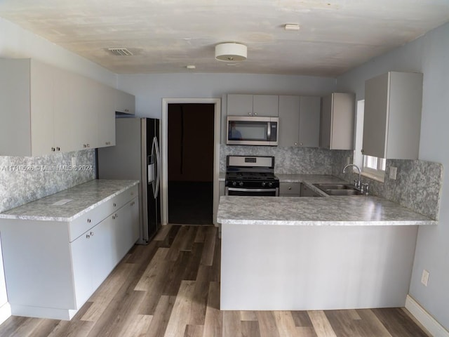 kitchen featuring kitchen peninsula, dark hardwood / wood-style flooring, stainless steel appliances, and sink