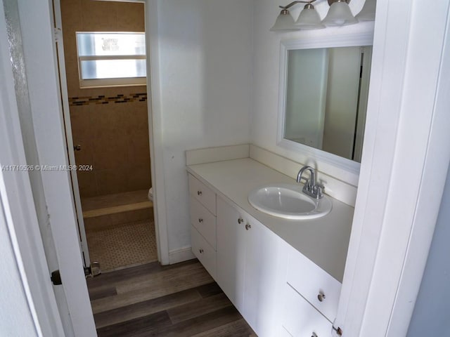 bathroom featuring tiled shower, hardwood / wood-style floors, vanity, and toilet