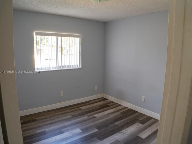 spare room with a textured ceiling and dark hardwood / wood-style flooring