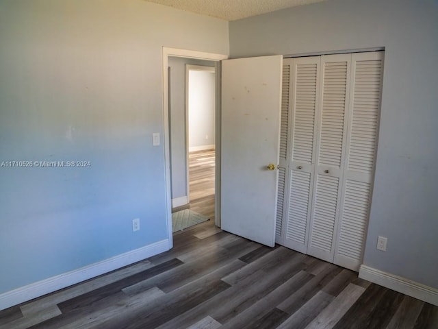 unfurnished bedroom with dark hardwood / wood-style flooring, a textured ceiling, and a closet