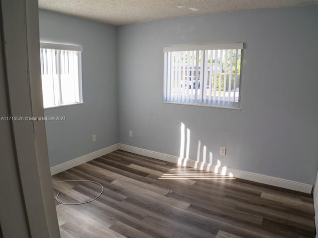 unfurnished room featuring a textured ceiling and dark hardwood / wood-style floors