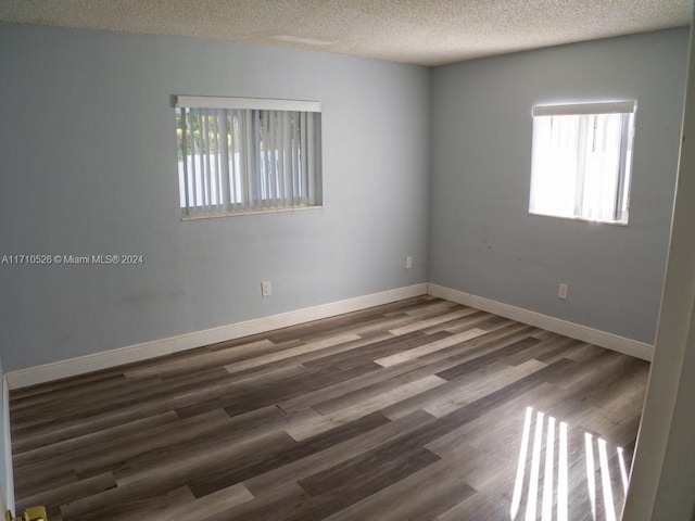 unfurnished room featuring dark hardwood / wood-style floors and a textured ceiling