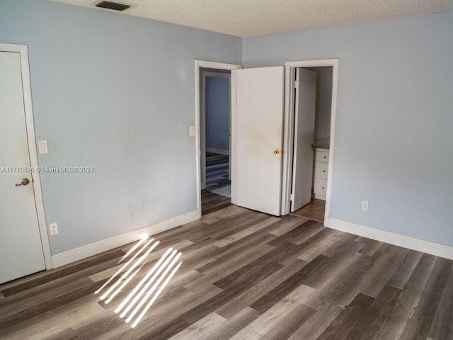 unfurnished bedroom with dark hardwood / wood-style flooring and a textured ceiling