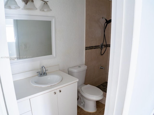 bathroom featuring tile patterned floors, vanity, toilet, and a tile shower