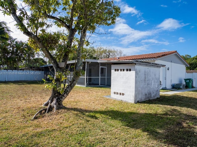 rear view of house featuring a sunroom and a lawn