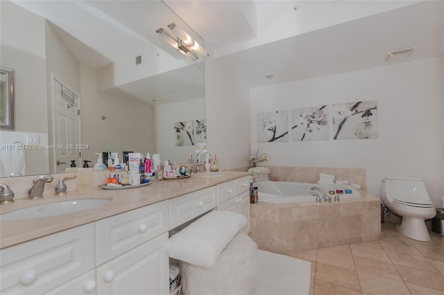 bathroom featuring tile patterned floors, vanity, toilet, and tiled bath