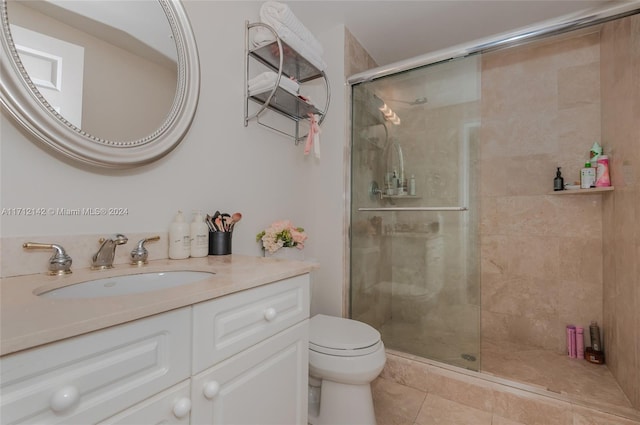 bathroom featuring tile patterned flooring, vanity, a shower with shower door, and toilet