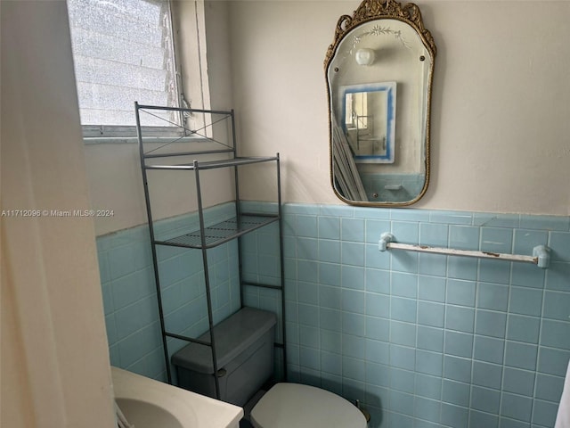 bathroom with vanity, toilet, and tile walls