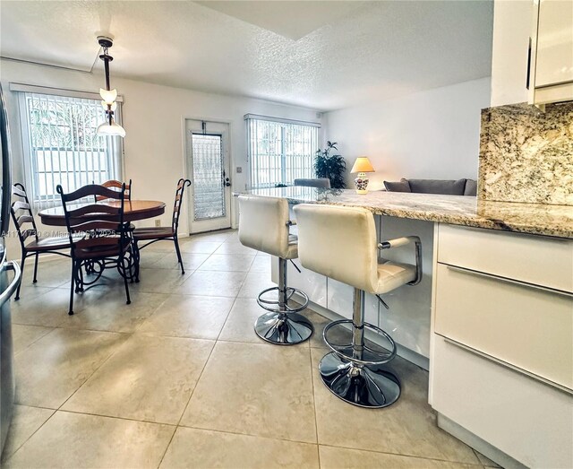 kitchen with white cabinetry, stainless steel appliances, backsplash, kitchen peninsula, and decorative light fixtures