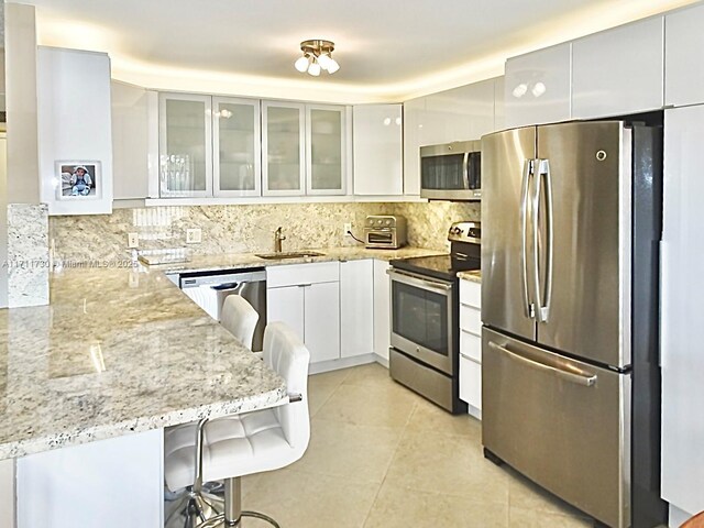 1016 Newcastle A 1016, Boca Raton, FL 33434 - kitchen with appliances with stainless steel finishes, modern cabinets, light stone countertops, and white cabinetry