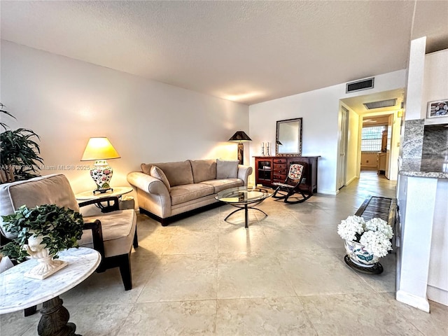 living area with a textured ceiling, visible vents, and baseboards