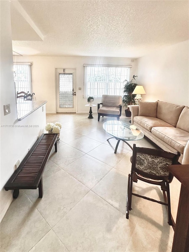 living room with a textured ceiling, light tile patterned floors, and a healthy amount of sunlight