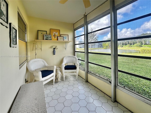 sunroom featuring a water view and a ceiling fan