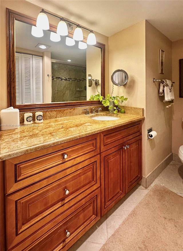 full bathroom featuring a closet, toilet, vanity, tiled shower, and tile patterned floors