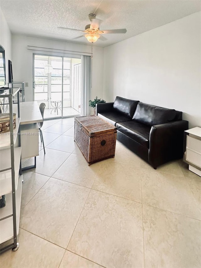 living room featuring light tile patterned floors, a ceiling fan, and a textured ceiling