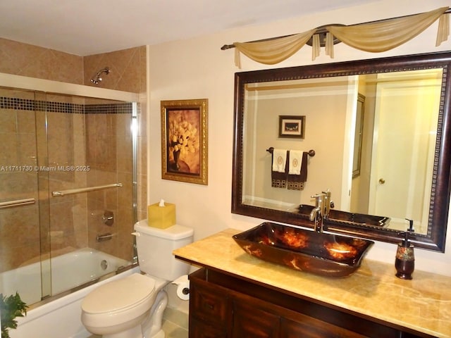 bathroom featuring toilet, bath / shower combo with glass door, and vanity