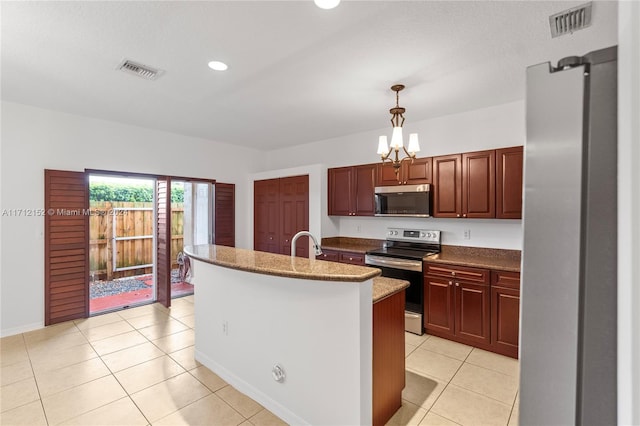 kitchen featuring an island with sink, a chandelier, decorative light fixtures, light tile patterned floors, and appliances with stainless steel finishes