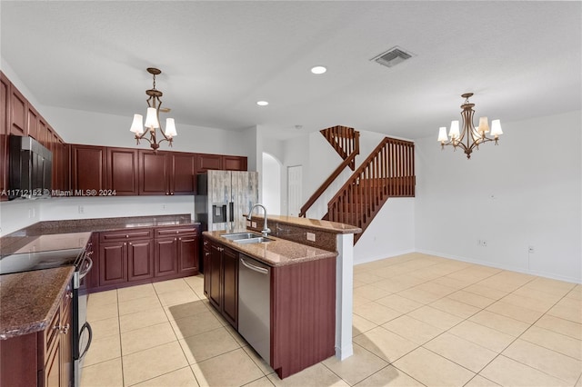 kitchen with pendant lighting, stainless steel appliances, an inviting chandelier, and an island with sink