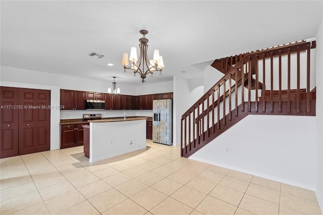 kitchen with an inviting chandelier, light tile patterned flooring, decorative light fixtures, a kitchen island, and appliances with stainless steel finishes