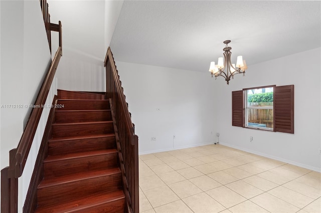 stairway with tile patterned floors and a notable chandelier