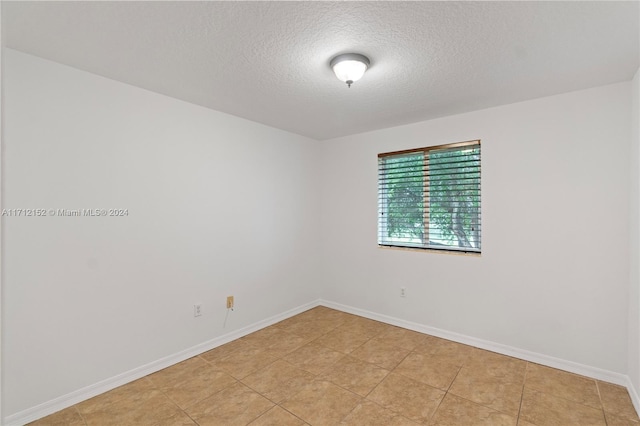 tiled spare room featuring a textured ceiling