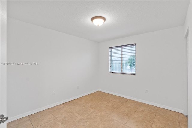 tiled empty room with a textured ceiling