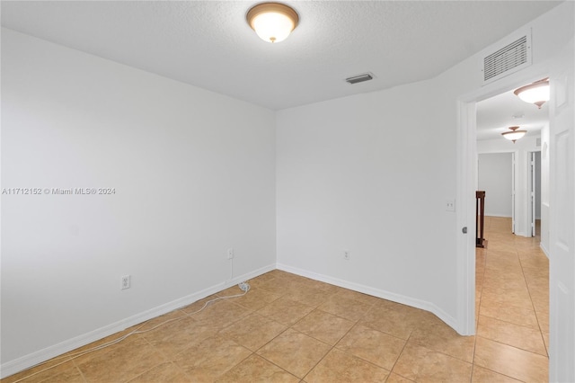 unfurnished room featuring light tile patterned floors and a textured ceiling