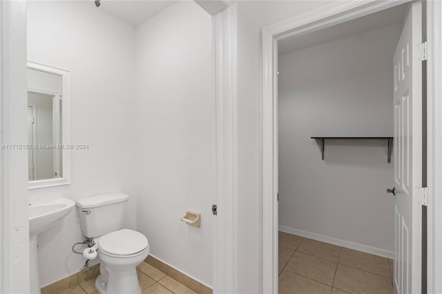 bathroom with toilet, tile patterned floors, and sink