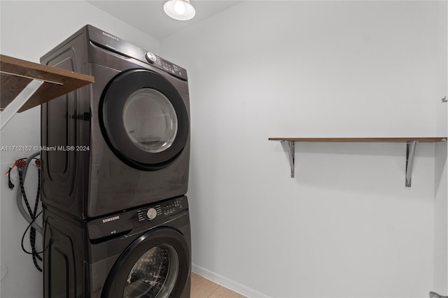 laundry area with light tile patterned floors and stacked washing maching and dryer