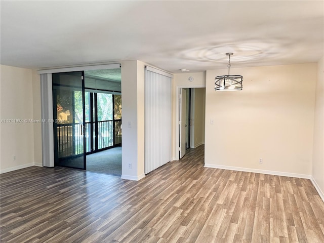 unfurnished room with wood-type flooring and an inviting chandelier