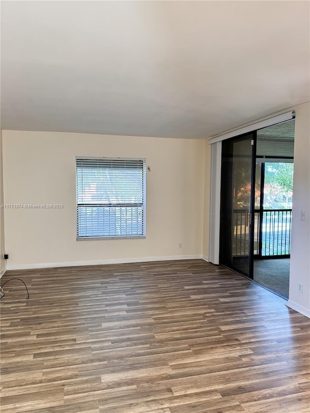 unfurnished room featuring expansive windows, baseboards, and wood finished floors