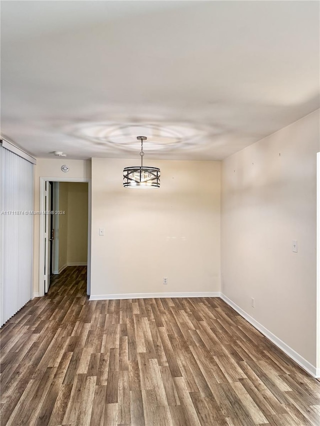 spare room with dark hardwood / wood-style floors and a notable chandelier