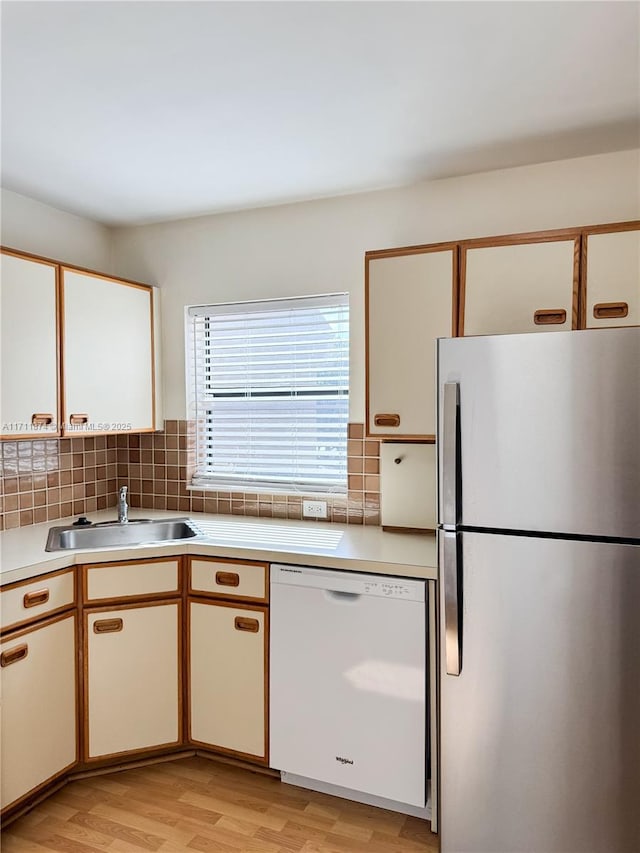 kitchen with dishwasher, backsplash, freestanding refrigerator, light countertops, and a sink