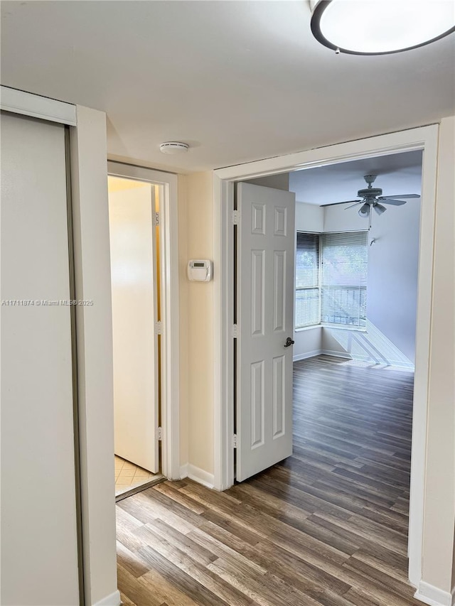 corridor with baseboards and wood finished floors